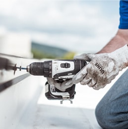 man using a drill for commercial roof maintenance