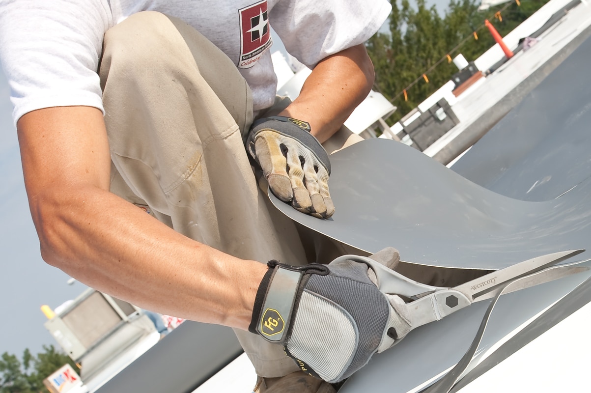 worker cutting tpo roofing